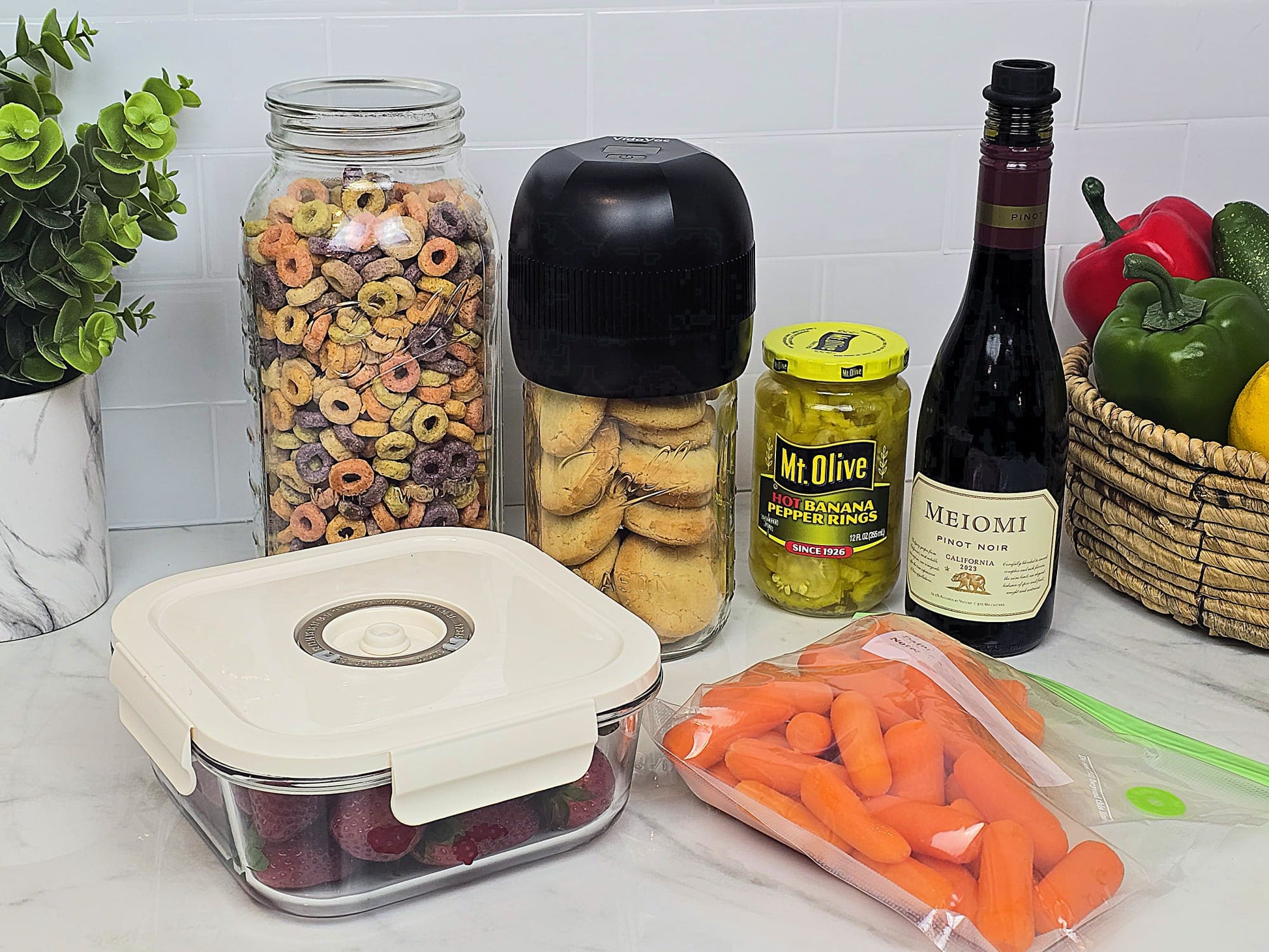 VidaVac vacuum sealer shown with jars, twist lid containers, vacuum seal bags, marinate container, and wine bottle — showcasing its multifunctional uses